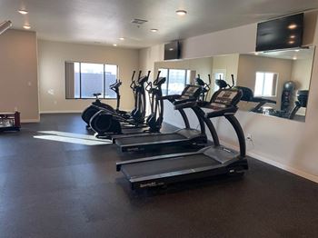 a row of treadmills in a gym with a large mirror on the wall at Beacon Estates Apartments, Fargo, 58103